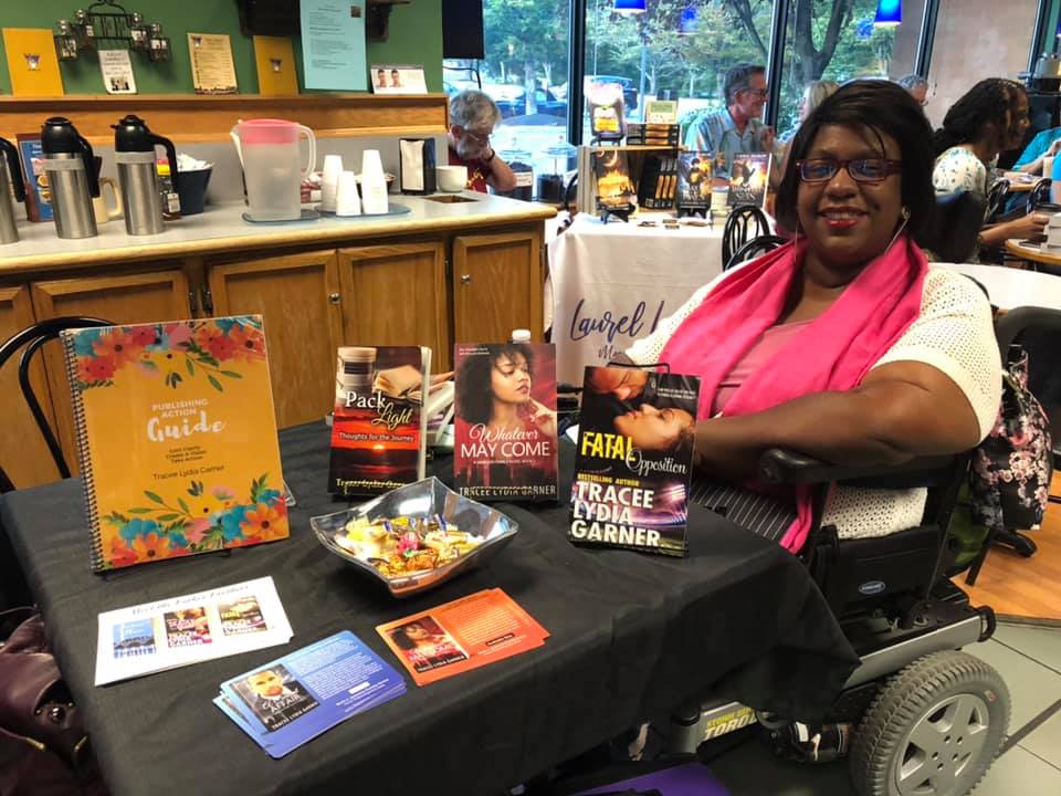 Tracee at table with her books, signing at local coffee shop event.